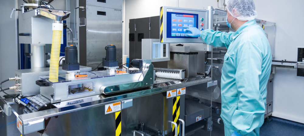 A pharmaceutical worker using a touch screen in a manufacturing facility, showing an electronic batch record system in use.