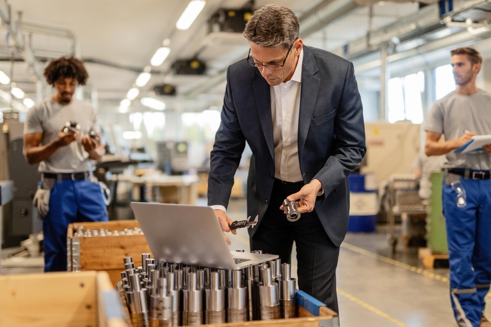 Manager examining parts in a factory setting to optimize manufacturing efficiency.