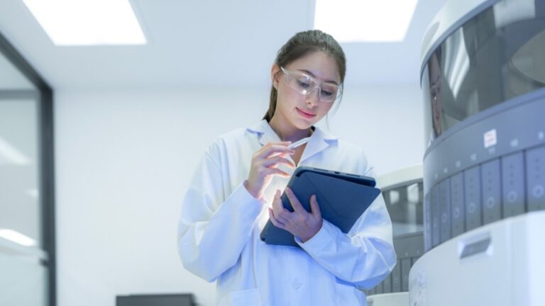 Biotechnology project management consulting 17 Pharmaceutical professional reviewing batch record data integrity on tablet in manufacturing facility for compliance and quality control